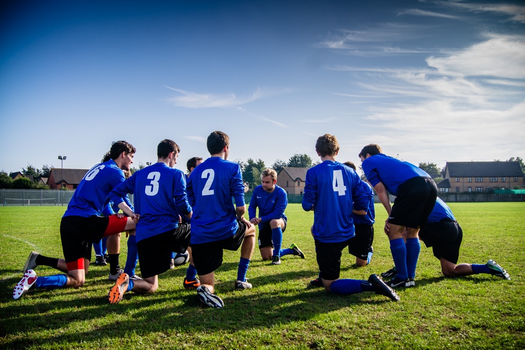 soccer players kneeling in blue uniforms on soccer field