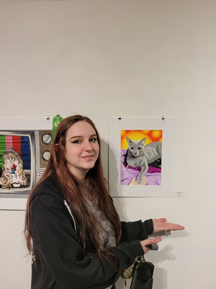Student standing next to art work